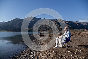 Man sitting in a camping chair while relaxing outdoors in nature.