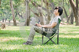 Man sitting on camping chair and working with laptop computer in the garden
