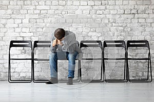 Man sitting on chair hunched after unsuccessful failed job interview