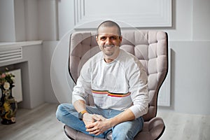 Man sitting on chair and smiling lookin in camera