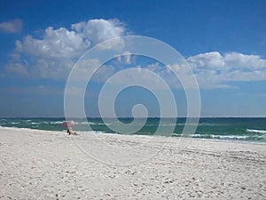 Man sitting in chair under beach umbrella on the beach.
