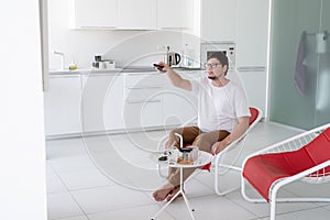 Man sitting in a chair watching tv holding remote control