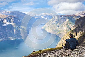 Man sitting on cliff edge alone enjoying aerial view backpacking lifestyle travel adventure outdoor summer vacations in