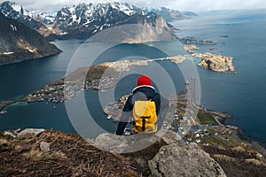 Man sitting on cliff edge alone enjoying aerial view backpacking lifestyle travel adventure outdoor vacations in Norway
