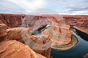 Man sitting on a cliff over Colorado river in Horseshoe bend canyon