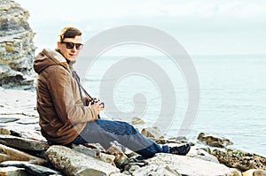 Man sitting on coastline with photo camera