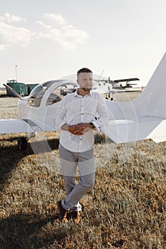 A man is sitting in the cockpit of his private plane. The pilot, against the background of the plane at sunset.