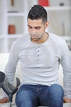 Man sitting on couch with crutches on side