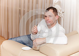 Man sitting on the couch drinking a cup of coofee