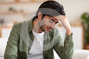 Man Sitting on Couch With Hand on Head