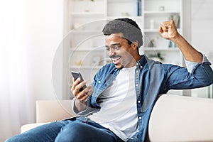 Man Sitting on Couch Holding Cell Phone, Gesturing