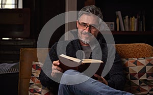 Man sitting on couch at home reading book