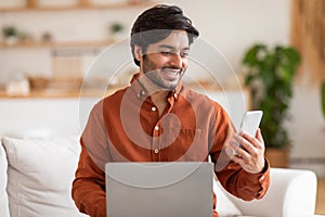 Man Sitting on Couch With Laptop and Mobile Phone