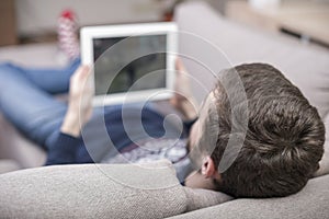 A man sitting on the couch uses a tablet PC. Back view.