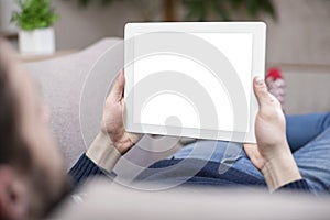 A man sitting on the couch uses a tablet PC. Back view.