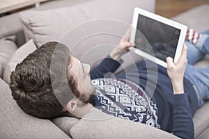 A man sitting on the couch uses a tablet PC. Back view.