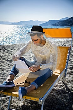 Man sitting on deckchair while reading letter