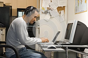 Man sitting at desk with computers.