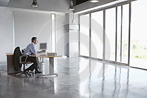 Man Sitting At Desk In Empty Office