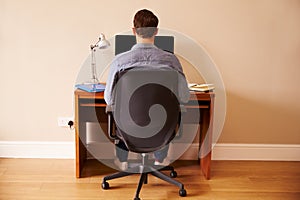 Man Sitting At Desk Working At Computer In Home Office