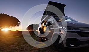 man sitting with digital device at his Transporter Camping Van bus at the California Ocean in the coastal Nature - digital nomades