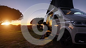 man sitting with digital device at his Transporter Camping Van bus at the California Ocean in the coastal Nature - digital nomades