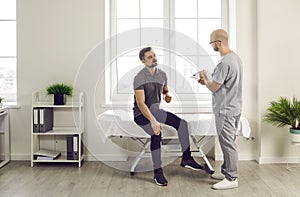 Man sitting in the doctor's office pointing to his knee during medical examination in clinic