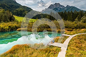 Man Sitting with Dog at Alpine Lake in Mountains. Traveling Together Concept