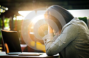 A man sitting down, his face unsettled. At the computer desk He has headaches and stress. Cause of hard work and insufficient rest