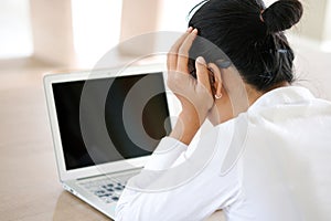 A man sitting down, his face unsettled. At the computer desk He has headaches and stress. Cause of hard work and insufficient rest