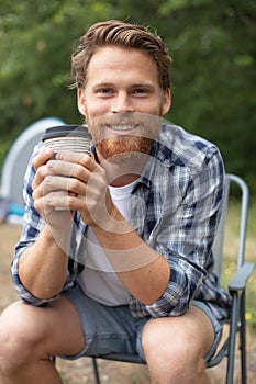 man sitting drinking tea or coffee on campsite photo