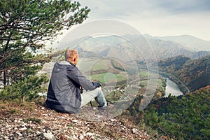 Man sitting on the edge of the cliff above mountaine valley photo