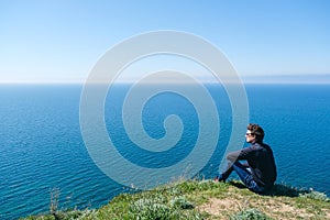 Man sitting on edge of cliff at edge