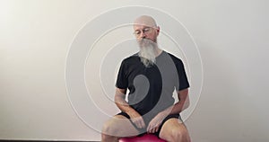 Man sitting on fitness ball doing neck spine exercise