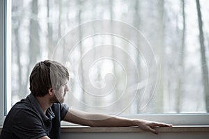 Man sitting on the floor of living room with big window
