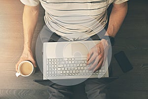 Man sitting on the floor and using laptop computer at home