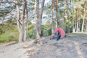 Man sitting in the forest near the tent