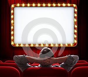 Man sitting in front of lighted sign on red theatre curtain photo