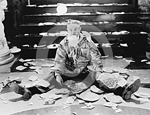 Man sitting in front of a staircase with broken plates around him