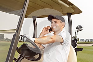 Man sitting in a golf cart and talking on phone