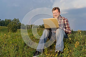 Man sitting on the grass with a laptop