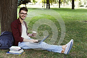 Man sitting on grass with laptop outdoors