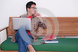 A man sitting on green sofa, working his office business on his laptop from home