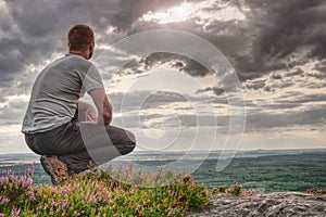 Man sitting on summit. He wear light clothes