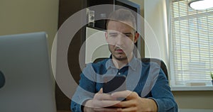 Man sitting at his desk home on desktop computer. Starts using smartphone, uses social media app, emailing business