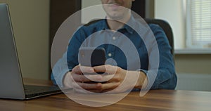 Man Sitting at His Desk home on Desktop Computer. Starts Using Smartphone, Uses Social Media App, Emailing Business