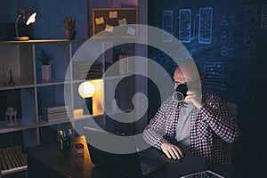 Man drinking coffee while working overtime