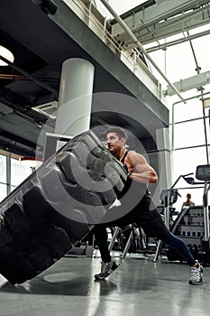 Man sitting on his toes holding a pair of battle ropes for workout. guy at the gym working out with fitness rope.