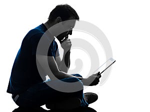 Man sitting holding watching digital tablet silhouette