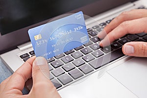 Man sitting with laptop and credit card shopping online